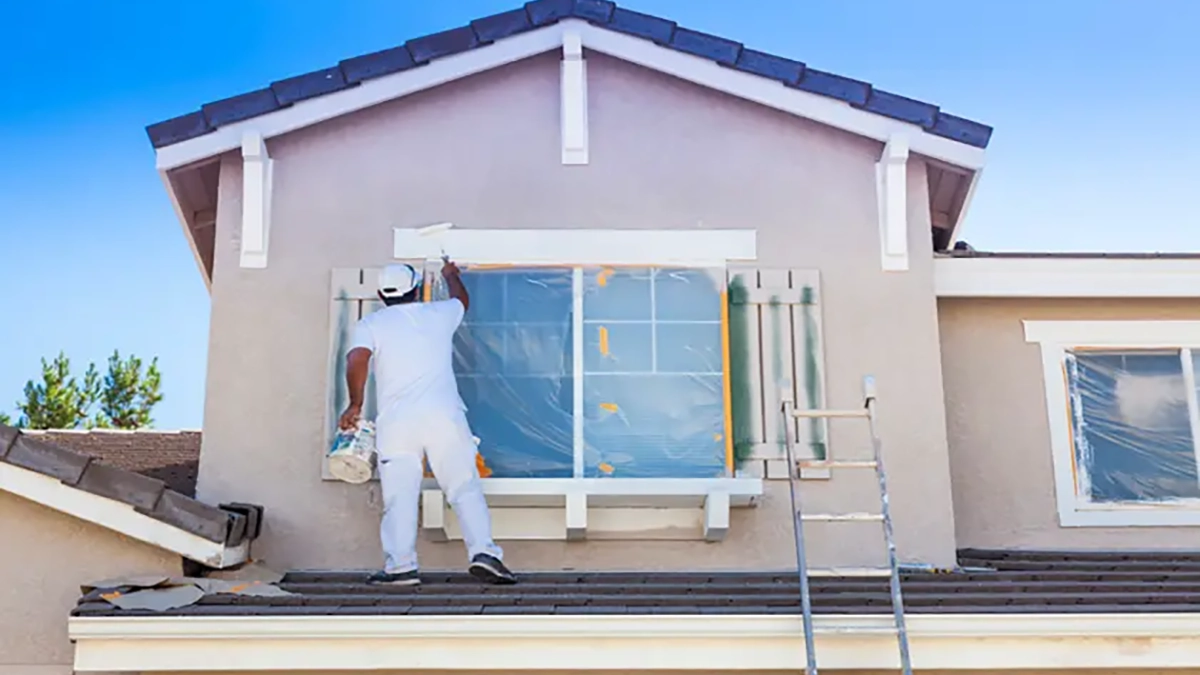 Cost to Paint House Exterior: Exterior Paint Cost Calculator. Man painting stucco exterior.
