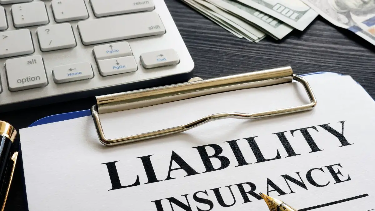 liability insurance paper near a white keyword and dollar bills